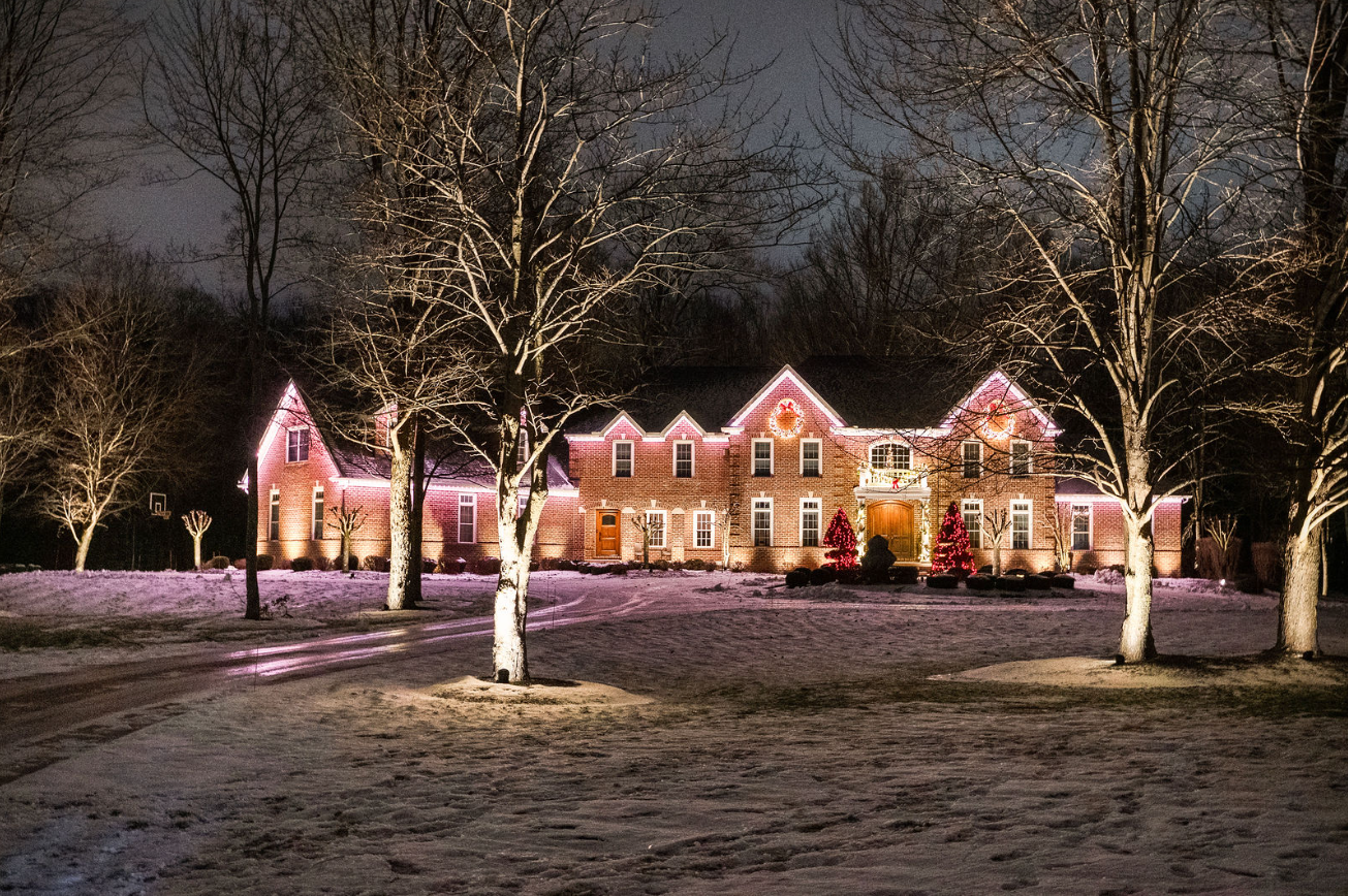Brick home illuminated with OELO permanent outdoor lighting and warm Christmas accents at night