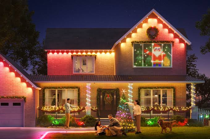 Brick home decorated with Govee permanent outdoor lights, colorful Christmas scenes, and a family enjoying the display at night